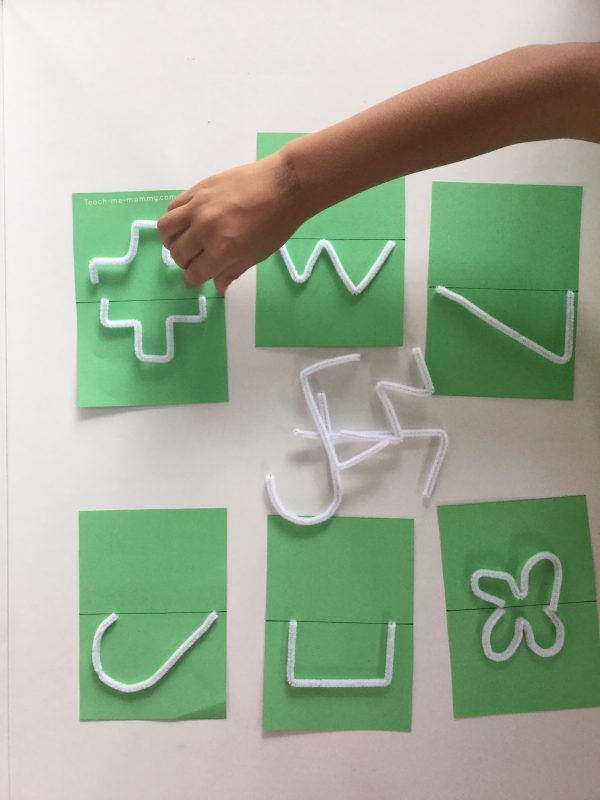 someone is cutting out letters and shapes from green paper with white plastic cutters on them