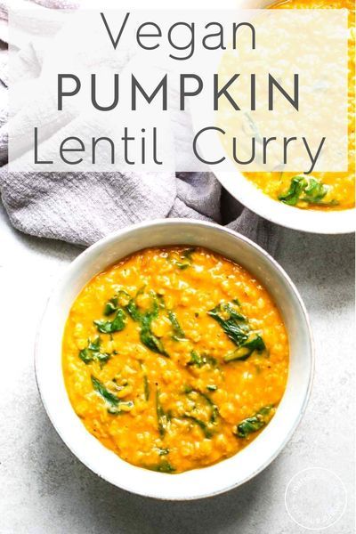 two bowls filled with pumpkin lentil curry on top of a white tablecloth and napkins