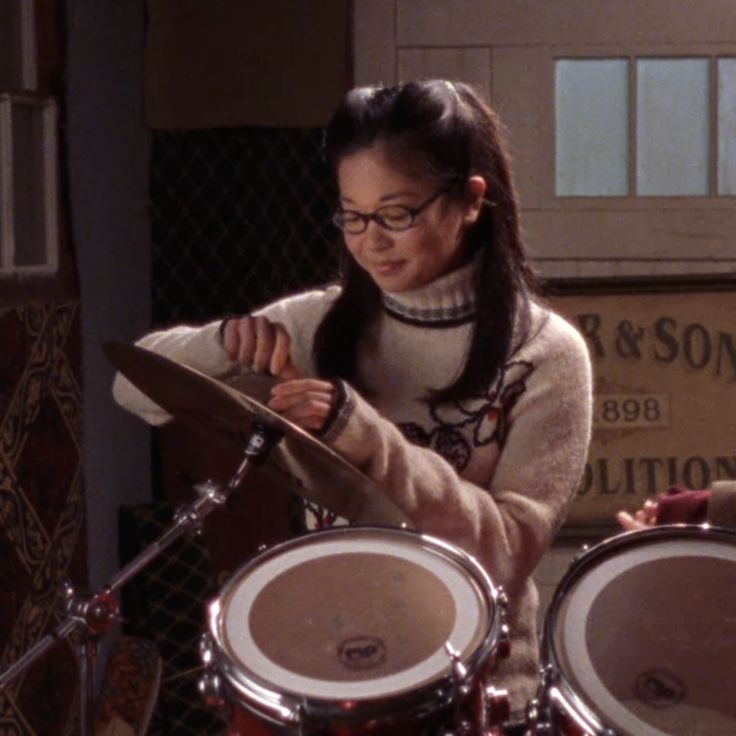 a woman with glasses is playing the drums