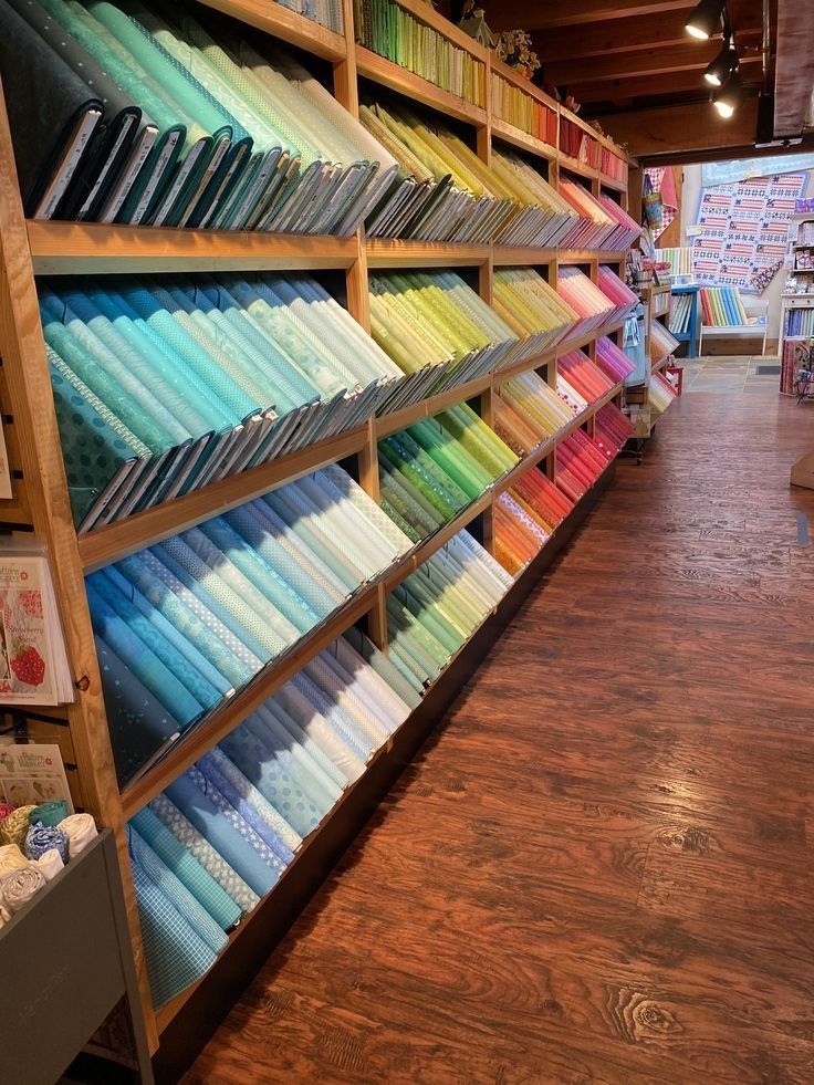 the shelves are filled with many different colored fabrics and papers on display at the store