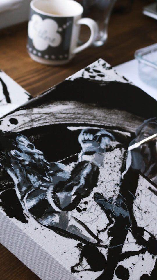 a close up of a painting on a table next to a cup and coffee mug