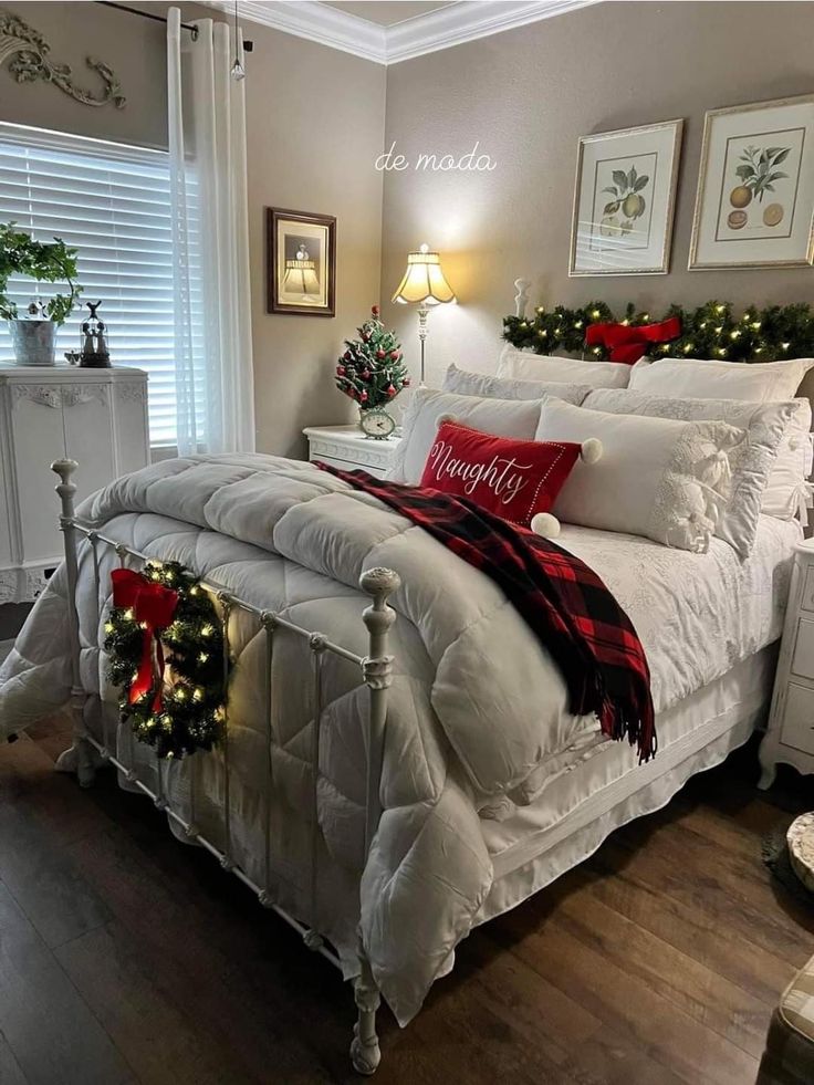 a bedroom decorated for christmas with white bedding and holiday decorations on the headboard