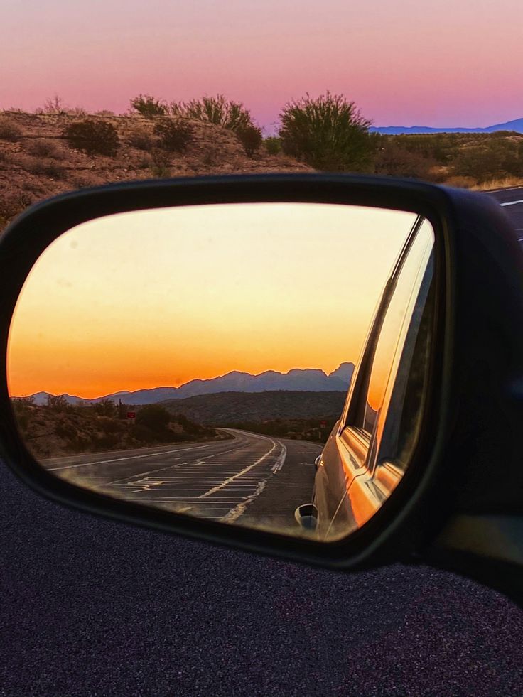 a car's rear view mirror reflecting the sunset