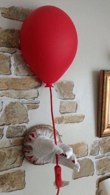 a red balloon attached to a wall with a white horse head on it and a mirror