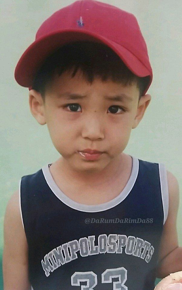 a young boy wearing a red hat and holding a doughnut in his hand while looking at the camera