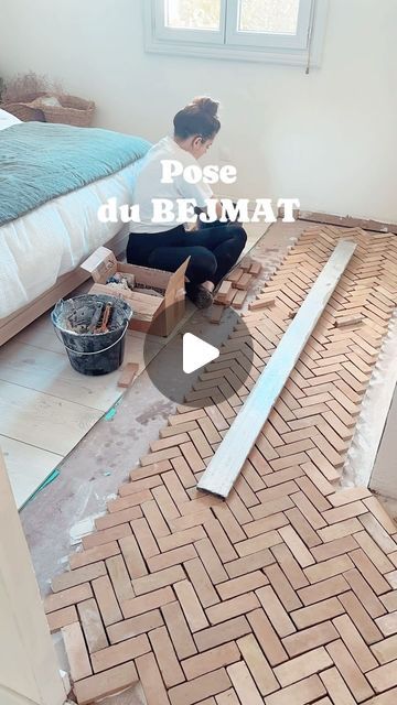 a woman kneeling on the floor in front of a bed and making a herringbone pattern