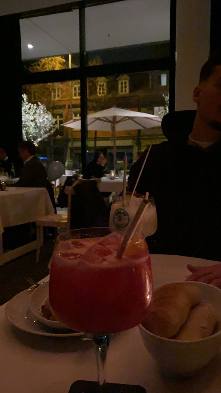 a person sitting at a table in front of a bowl of food and a drink