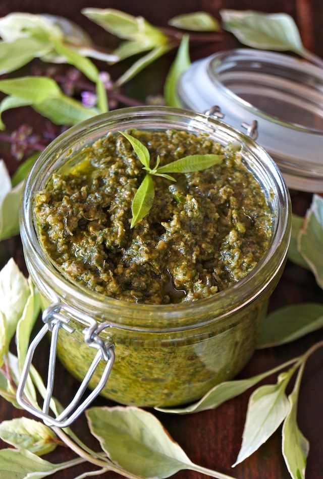 a jar filled with pesto next to some leaves