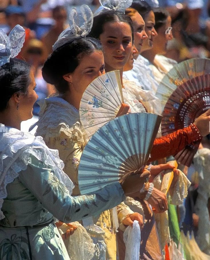 several women dressed in period costumes holding fans