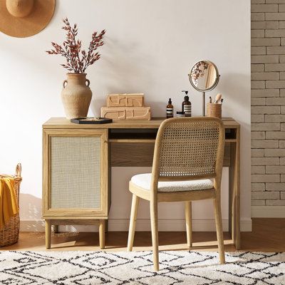 a desk with a chair, mirror and vase on it