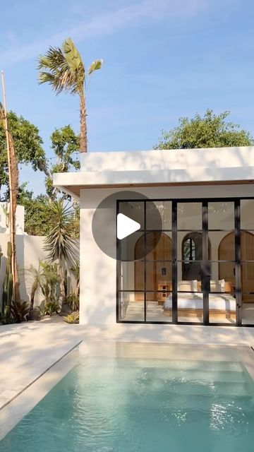 a house with a pool in front of it and palm trees around the pool area