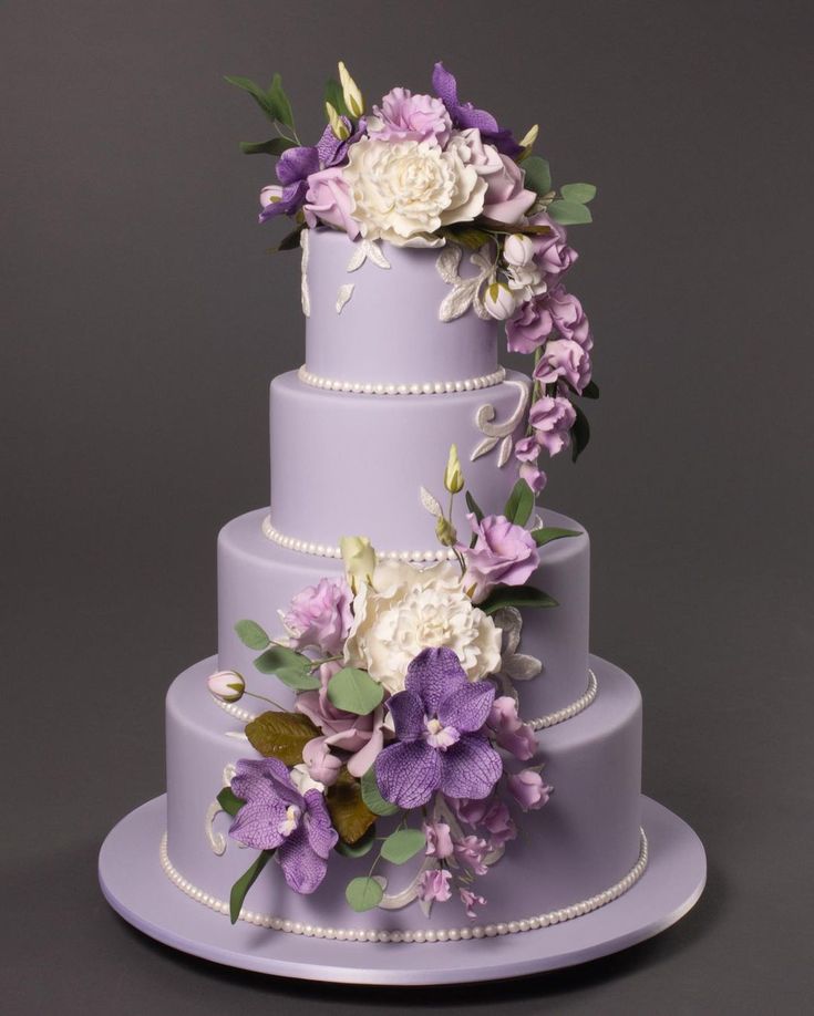 a three tiered cake with purple and white flowers