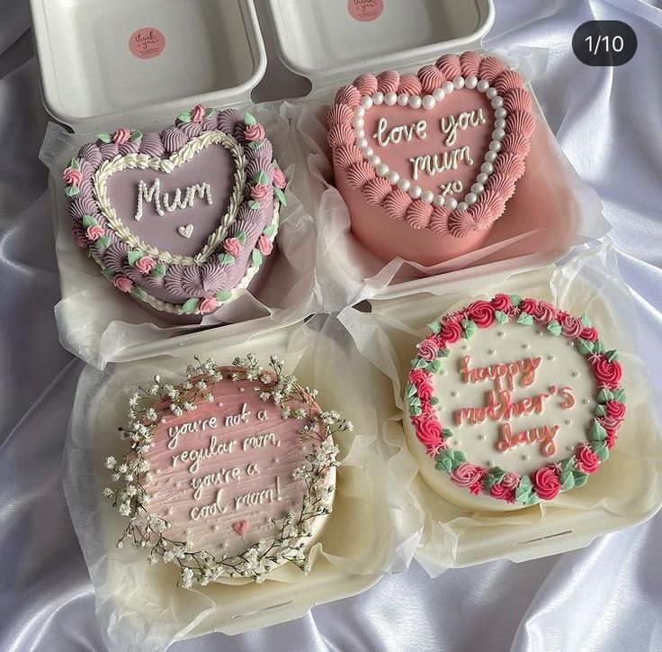 four decorated heart shaped cakes in plastic containers