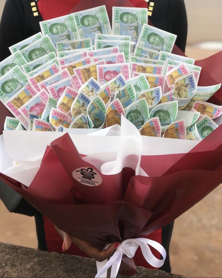 a man in uniform holding a bouquet full of money and wrapped in red paper with white ribbon