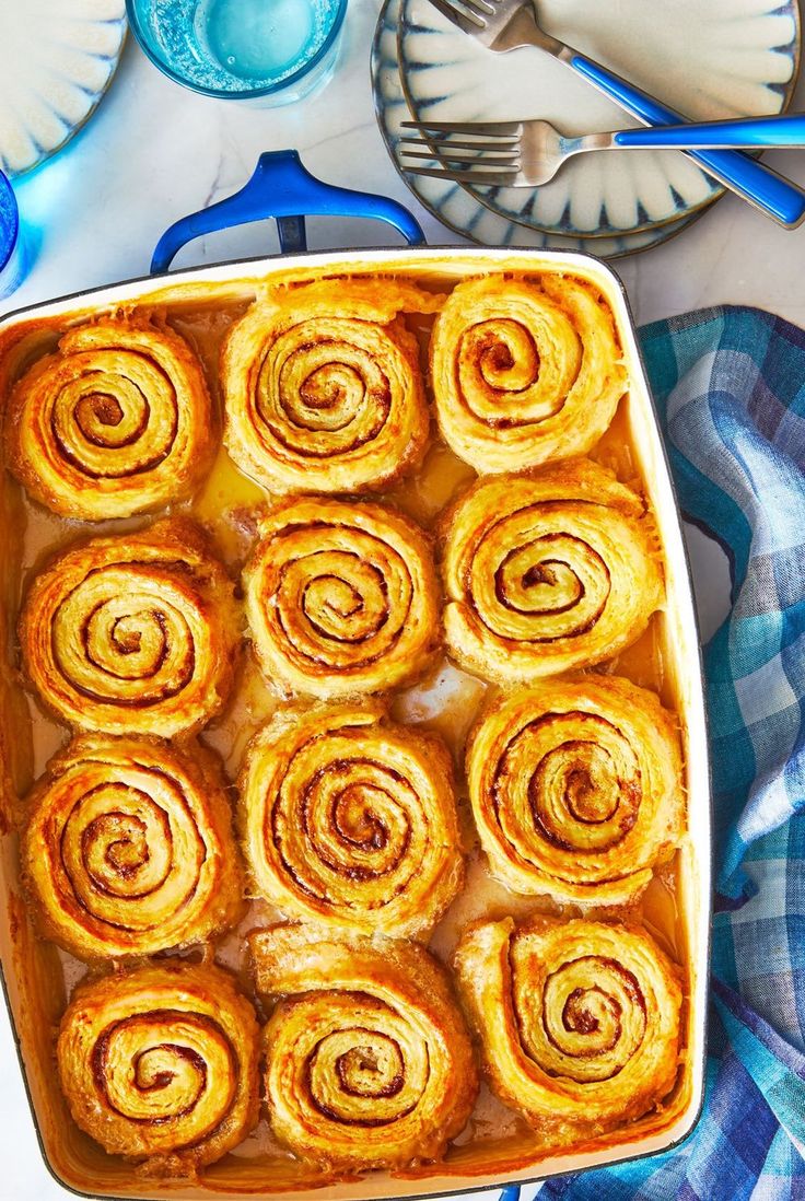 a pan filled with cinnamon rolls sitting on top of a blue and white table cloth