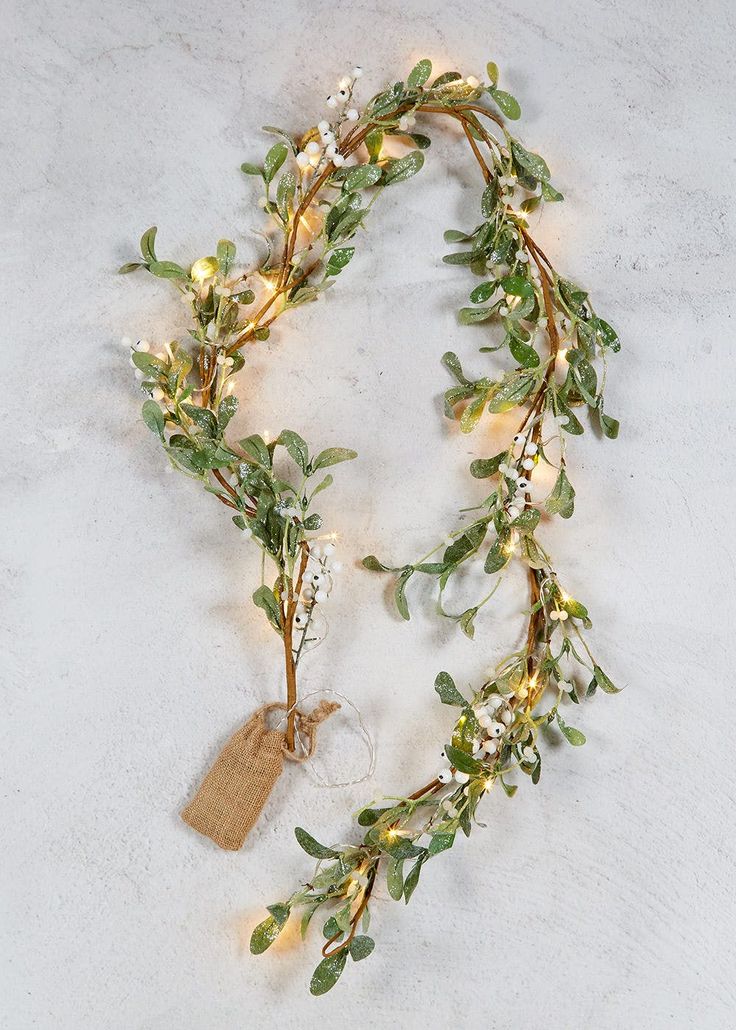 a green garland with white lights and greenery on the end is laying on a marble surface