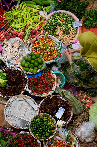 a woman standing in front of baskets filled with vegetables