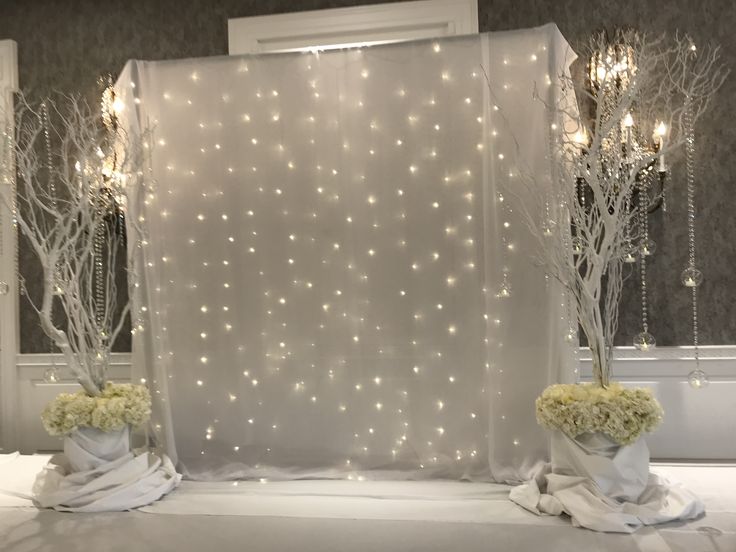 two vases filled with flowers sitting on top of a table next to a white curtain