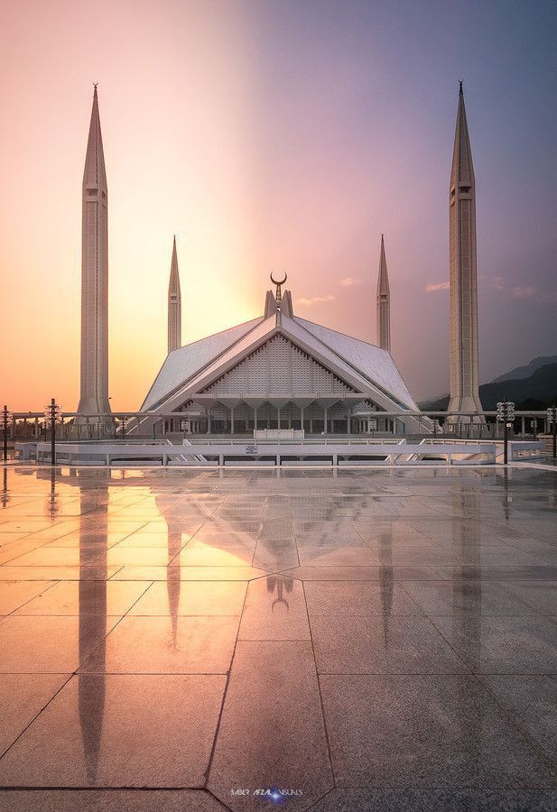 the sun is setting in front of a large building with two spires on each side