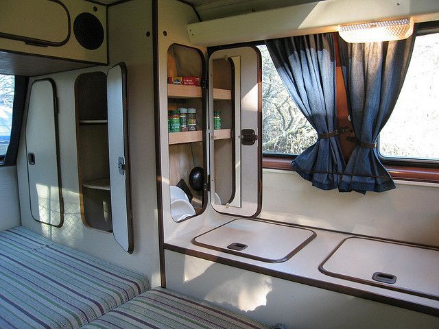 the inside of a camper that is parked in front of a window with curtains on it