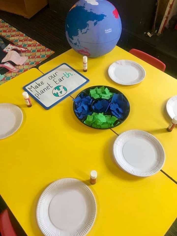 a yellow table topped with plates covered in paper and a blue globe on top of it