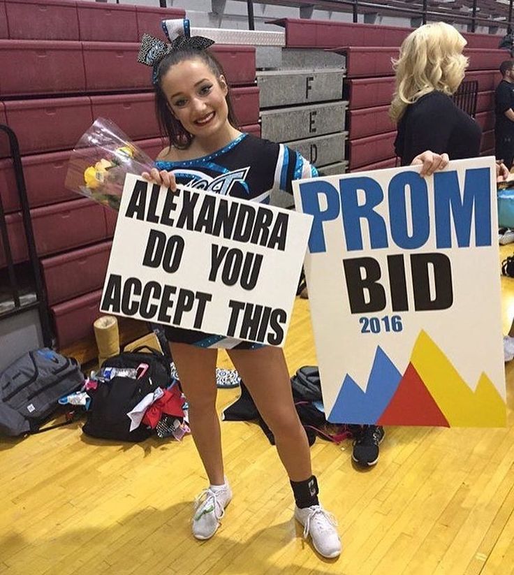 two cheerleaders hold up signs in the gym for prom and prom night celebrations