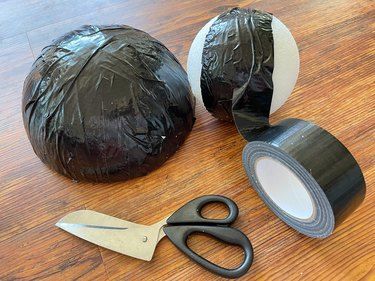 a pair of scissors and tape sitting on top of a wooden table next to a bag