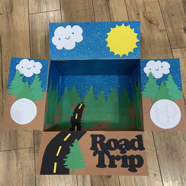 an open cardboard box with road trip cut out on the inside and trees in the middle