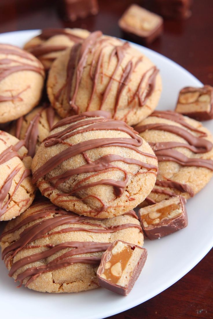 a plate full of cookies with chocolate drizzled on top and peanut butter in the middle