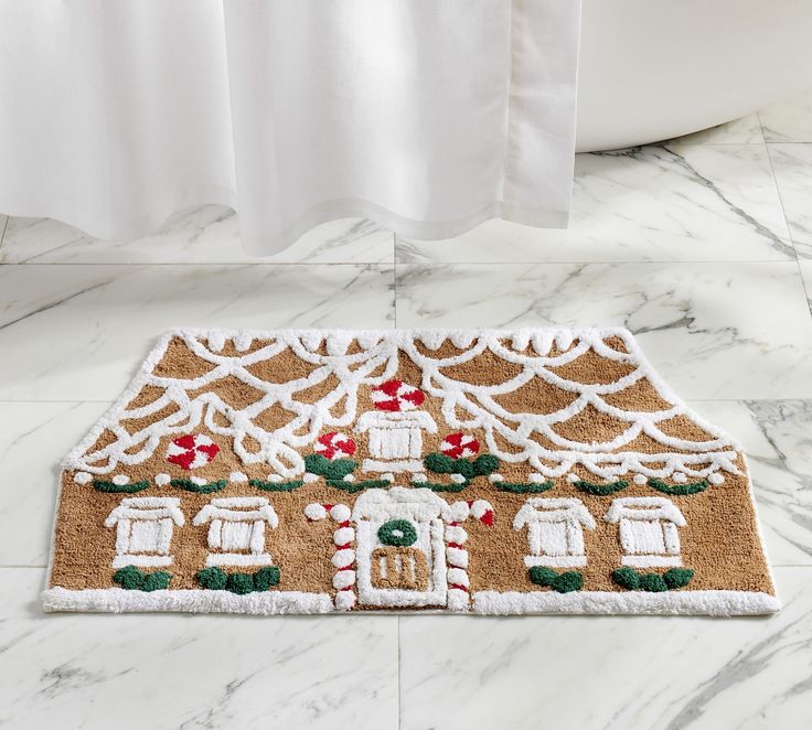 a gingerbread house door mat on the floor in front of a bathtub and shower curtain