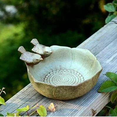 a bowl sitting on top of a wooden table next to green leaves and trees in the background