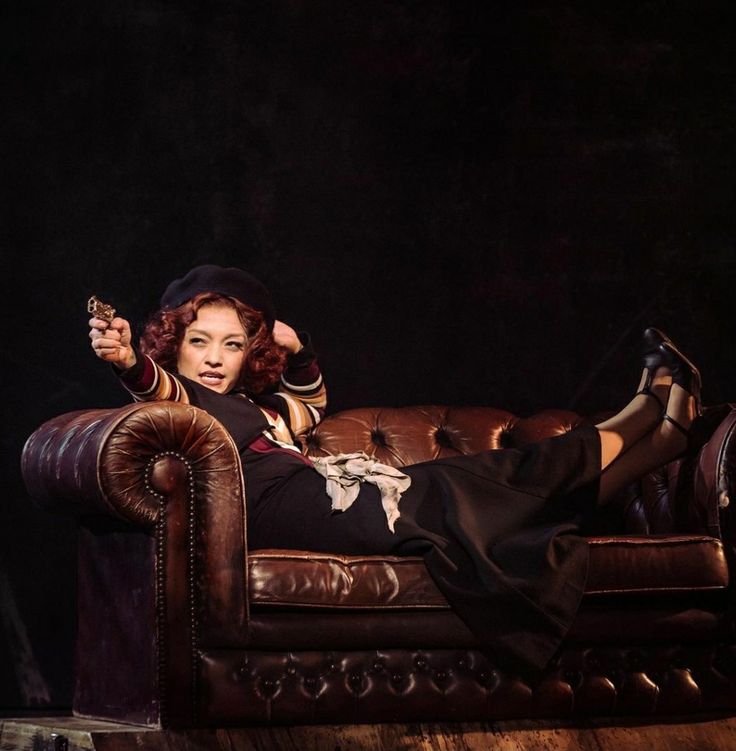 a woman laying on top of a brown couch