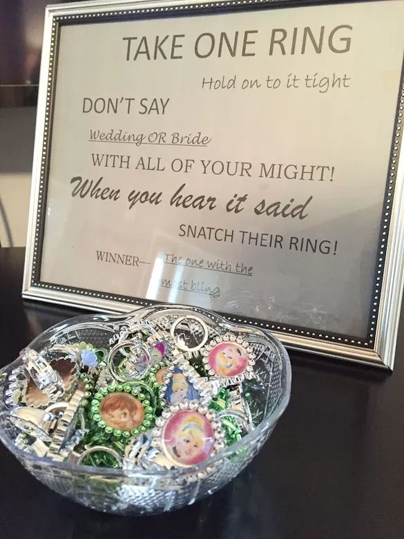 a glass bowl filled with lots of buttons on top of a table next to a sign that says, take one ring