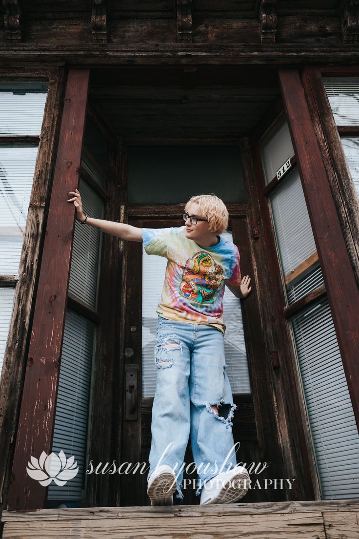 a young boy is standing on the front steps of an old wooden building with his arms outstretched