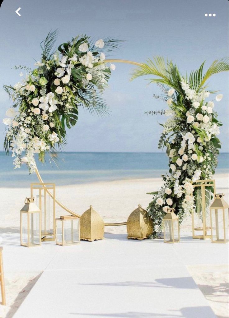 an aisle decorated with white flowers and greenery at the end of a beach wedding ceremony