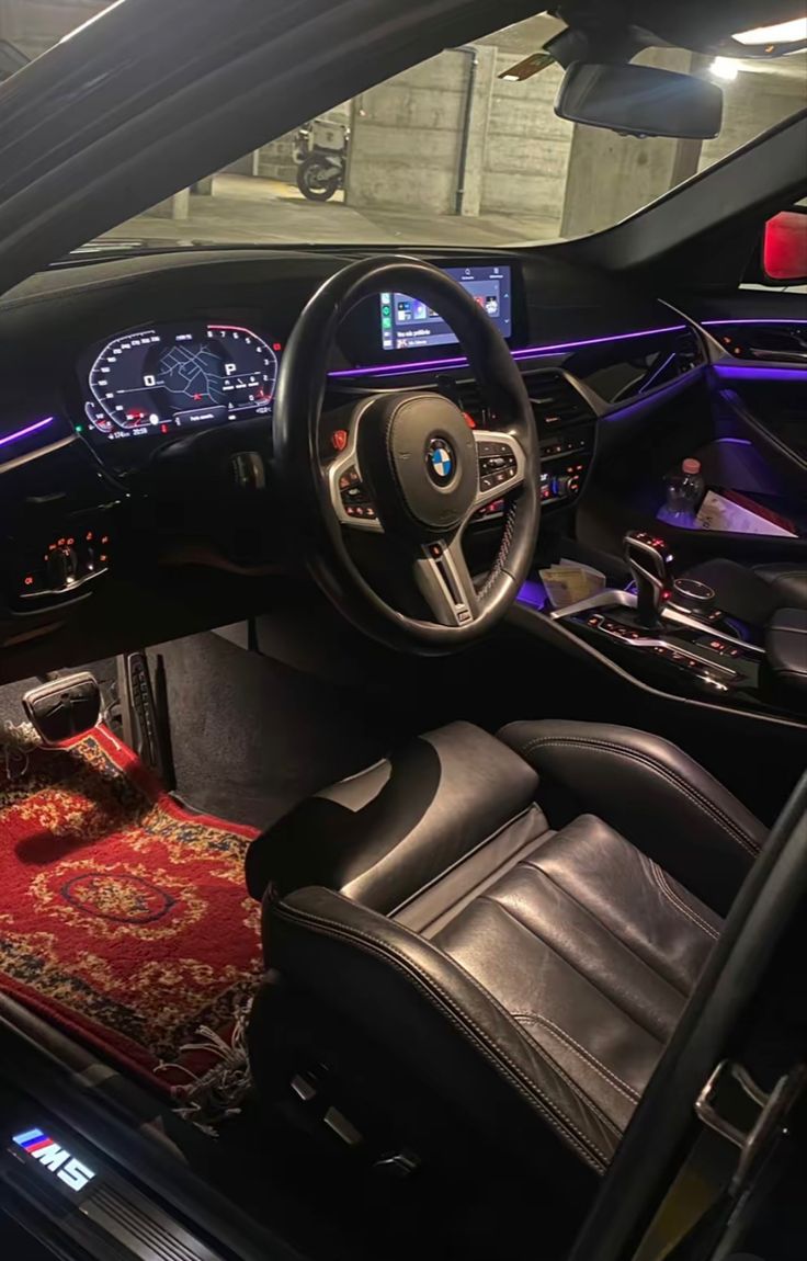 the interior of a car with black leather seats and red carpeted area rugs