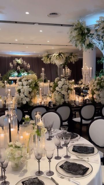 a table set up with white flowers and candles