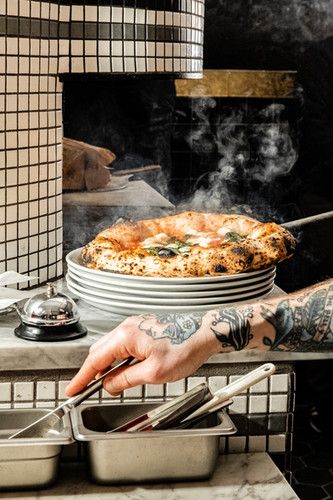 a man with tattoos is cooking food in the kitchen