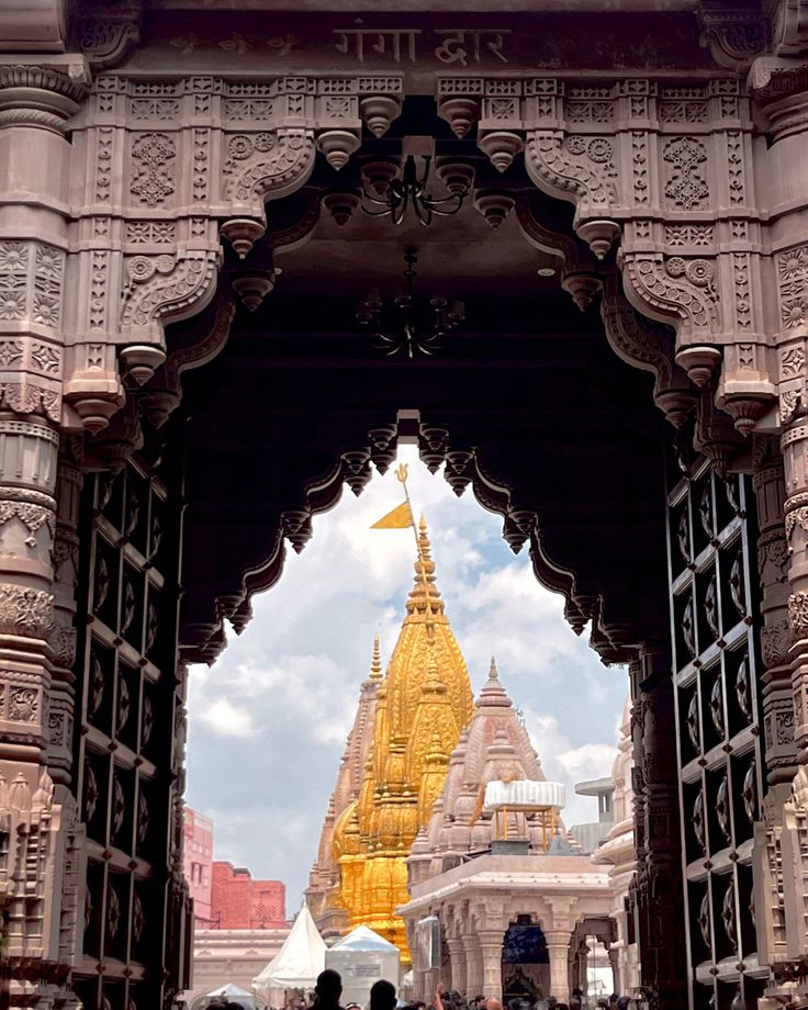 the entrance to an ornate building with people walking through it and looking at something in the distance