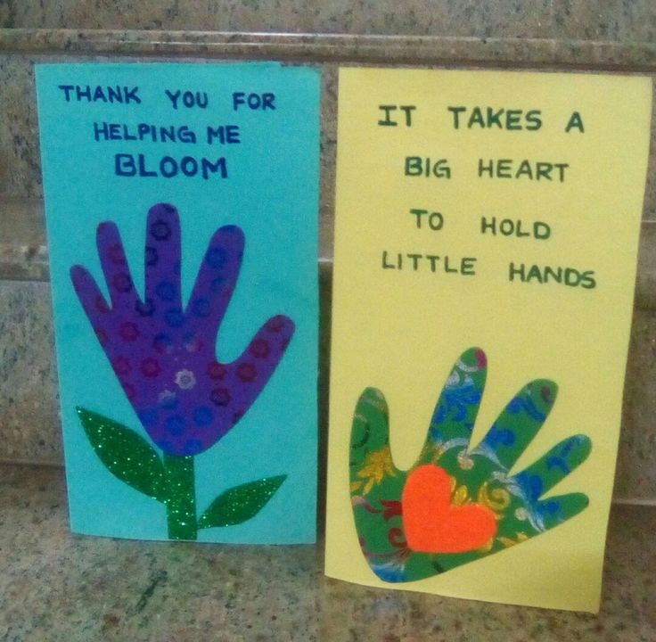 two handprinted cards are sitting on the counter next to each other, one has a flower and the other says it takes a big heart to hold little hands