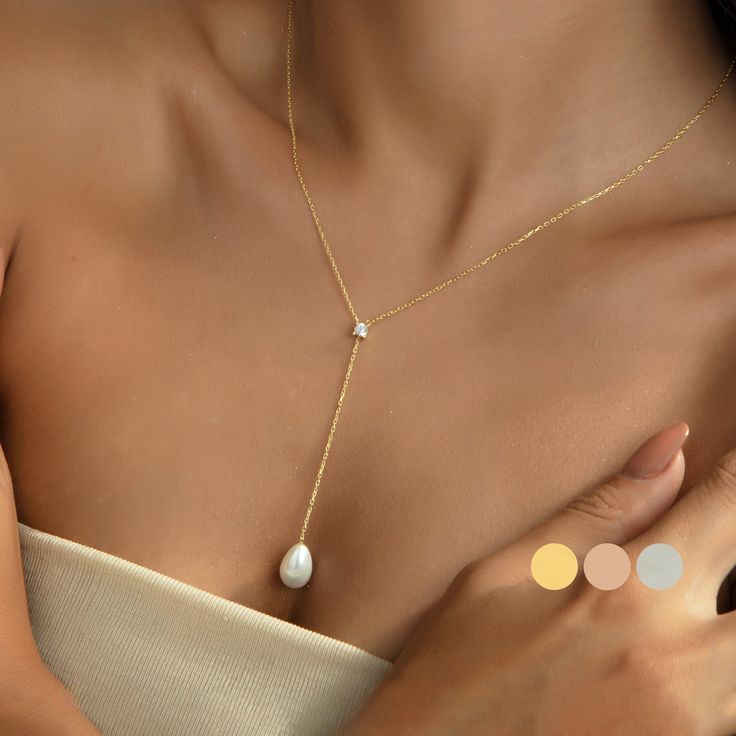 "14K Gold Plated Pearl Necklace, Wedding Gift, Tiny Pearl Lariat Necklace, Drop Necklace, Layering Necklace, Bridesmaid Gift, Gift for Her - DAINTY ∙ PEARL ∙ LARIAT ◇ ◇ Stone: A CZ stone and a freshwater pearl. ◇ Materials: 925K Sterling Silver with Yellow Gold Plated, Rose Gold Plated, White Gold Plated ♡ HOW ∙ TO ∙ ORDER → → STEP 1: Choose your Chain Length. → STEP 2: Please select your preferred material color, ♡ CHAIN ∙ SIZE ∙ GUIDE ✣ ✣ 14\" NECKLACE: Fits most like a choker ✣ 16\" NECKLACE: Falls perfectly around the base of the neck like a collar. On a petite woman, it will hit your collarbone while for plus-size women it might feel more like a choker. ✣ 18\" NECKLACE: A common choice for women that will fall just below the throat at the collarbone. This length is popular for adding Silver Pearl Pendant Lariat Necklace For Wedding, Silver Lariat Necklace With Pearl Pendant For Wedding, Wedding Pearl Chain Drop Necklace, Elegant Drop Necklace For Wedding, Elegant Lariat Drop Necklace For Wedding, Wedding Drop Necklace With Pearl Chain, Lariat Pearl Necklace For Wedding, Adjustable Backdrop Necklace With Pearl Pendant As Gift, Adjustable Backdrop Necklace With Pearl Drop For Gifts