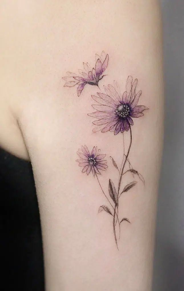 a woman's shoulder with three flowers on the left side of her arm and one flower in the middle