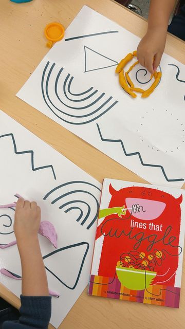 two children working on their art project at a table with paper cut outs and scissors