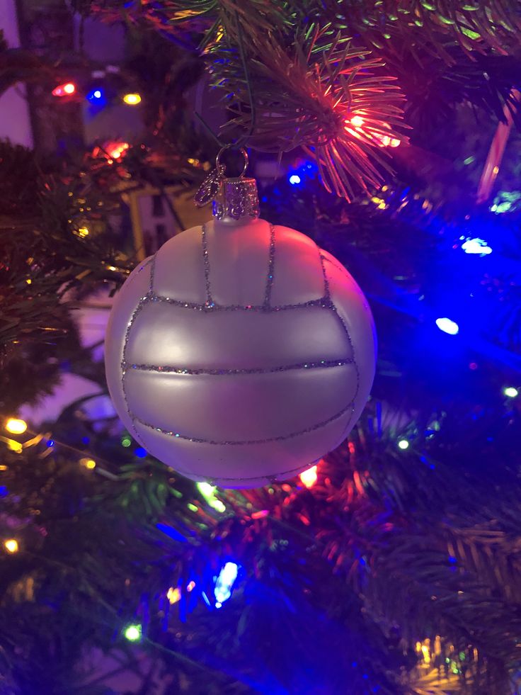 an ornament hanging from the top of a christmas tree with lights in the background