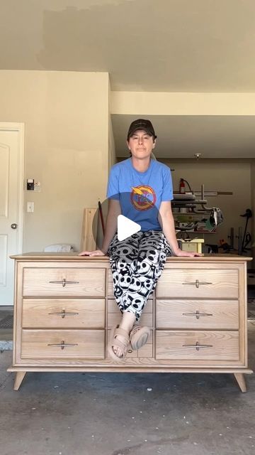 a woman sitting on top of a wooden dresser