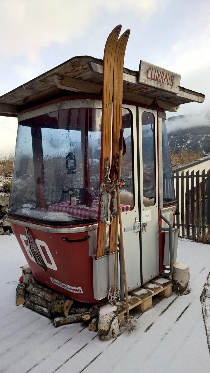 a red and white bus with skis on it's roof in the snow