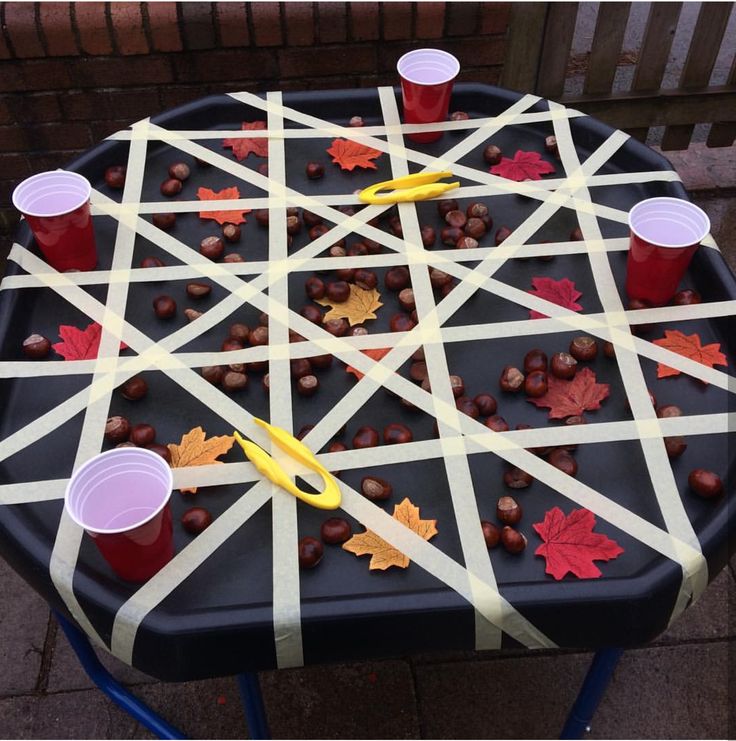 an outdoor game made out of sticks and plastic cups with fall leaves on them, sitting on a table