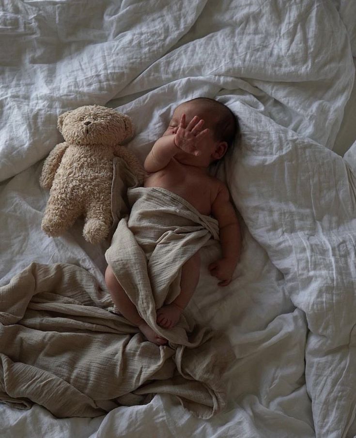 a baby is sleeping with a teddy bear