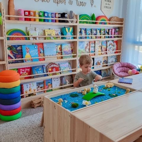 a young boy is playing with toys in a room full of children's books