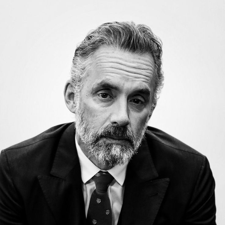 a black and white photo of a man with a beard wearing a suit jacket and tie